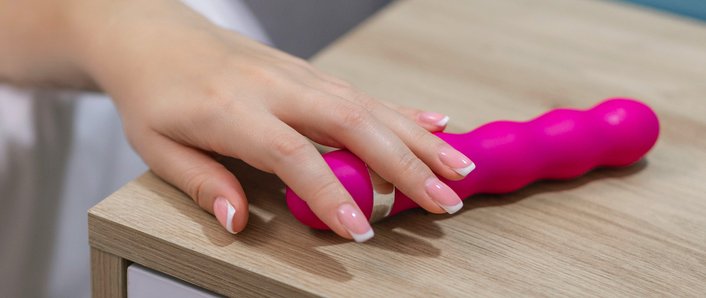 hand reaching for sex toy on bedside table