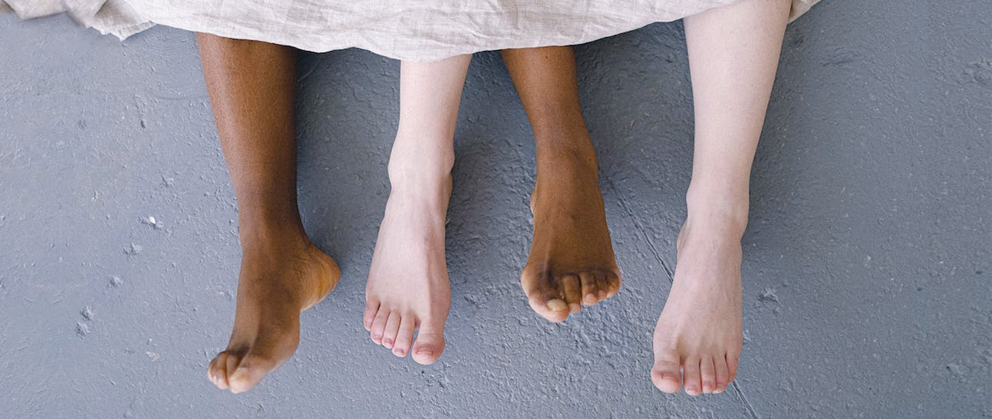 two sets of legs poking out from a bed